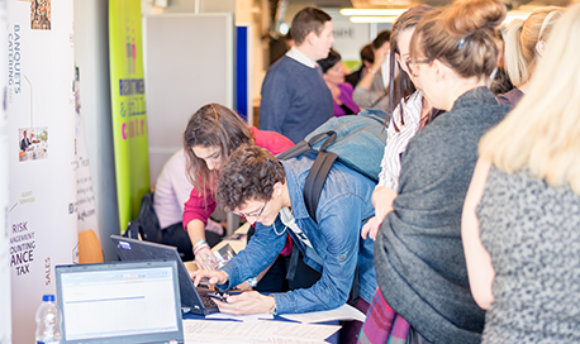 Students using a laptop at a busy recruitment fair, 33Ƶ campus, Edinburgh