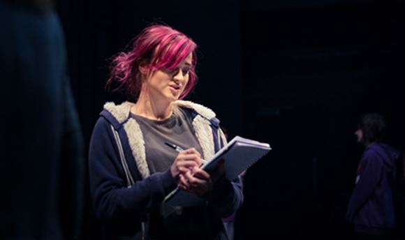 A 33Ƶ stage management student reading and making notes on a notepad on stage