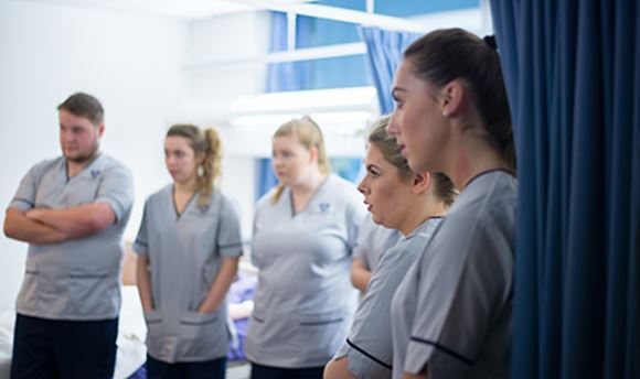 A row of 33Ƶ student nurses listening intently as a senior nurse speaks to them