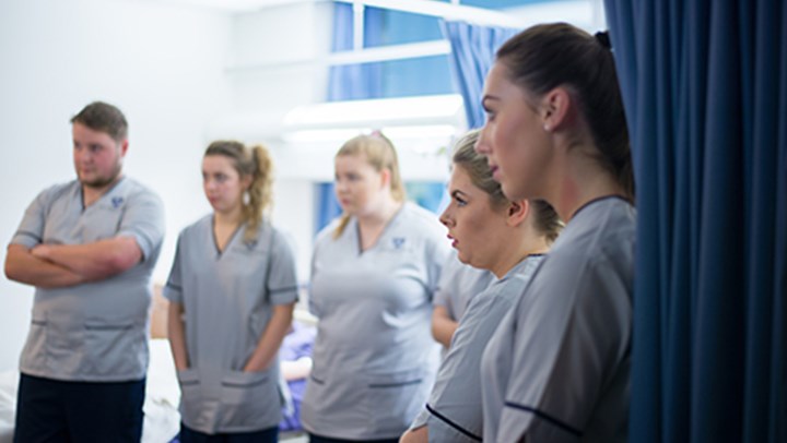 A row of 33Ƶ student nurses listening intently as a senior nurse speaks to them