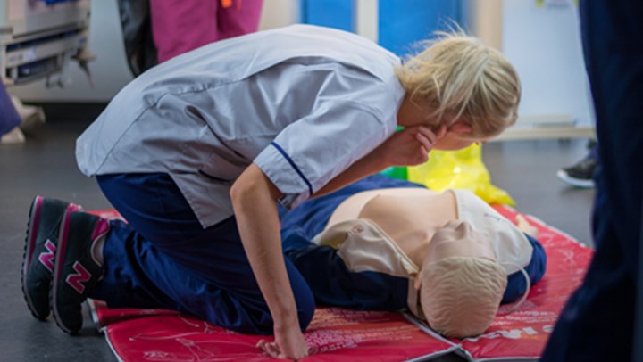 Queen Margaret University Nursing Student kneeling over a Resusci Annie doll