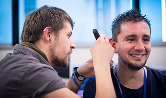 33Ƶ Hearing Aid Audiology student using a piece of equipment to test another student's hearing